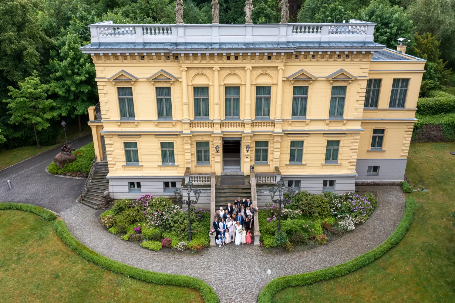 Drohnenblick, Luftaufnahmen von Hochzeitspaaren vor einem Gebäude mit Familie