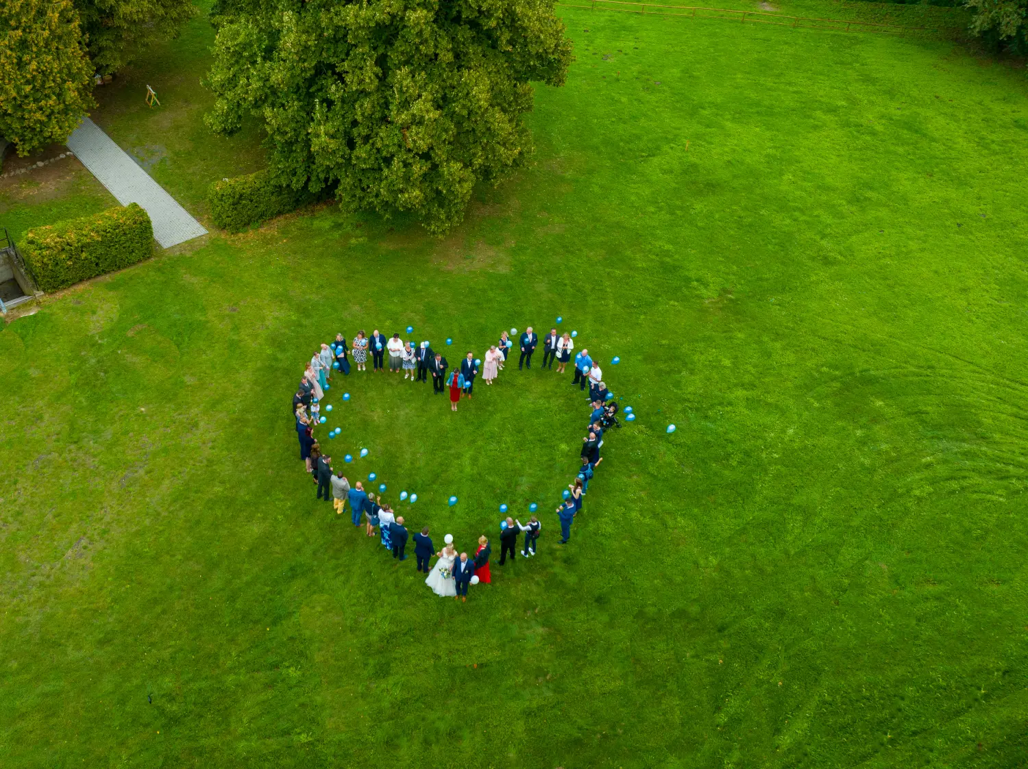 Drohnenblick, Luftbildaufnahmen von Gästen, die am Hochzeitstag ein Liebesherz bilden